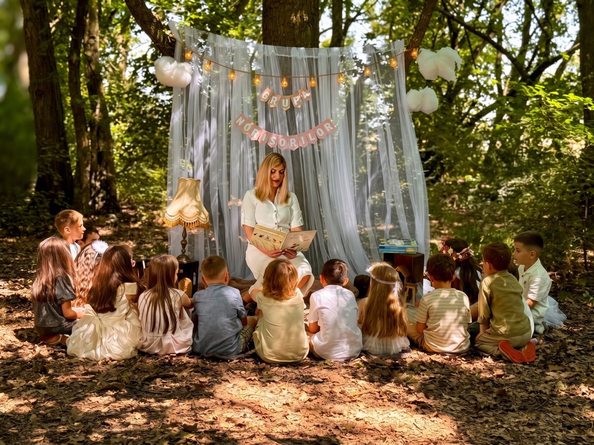 Educatoare citind o poveste unui grup de copii, în pădure, la Grădinița Amos